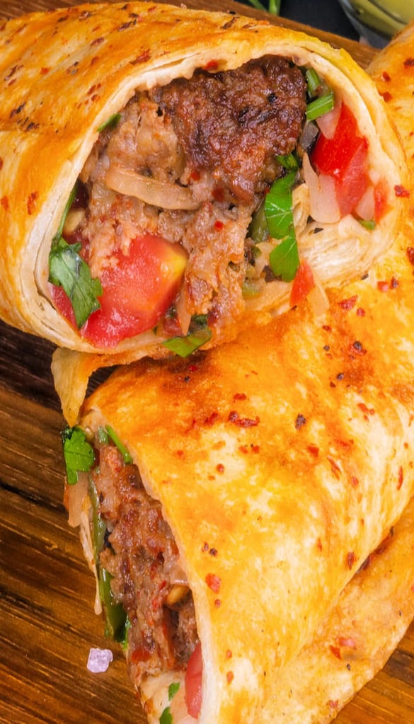 Close-up of Mediterranean wrap with grilled chicken, fresh vegetables, and spices